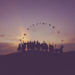 Graduates throwing their caps in the air during sunset