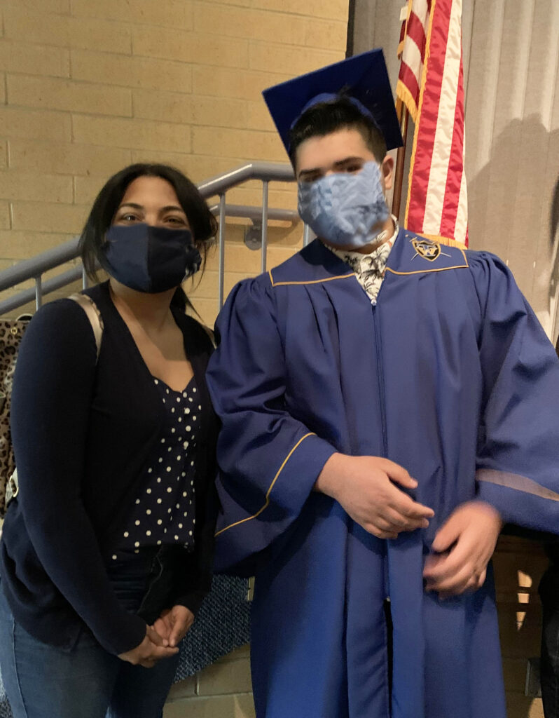 A guest stands with a student who just graduated from high school