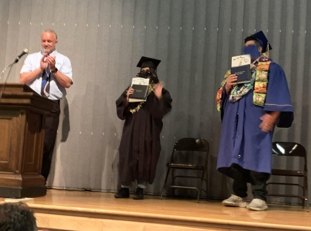 Jason, Associate Director of YESS, congratulates two students on stage at their graduation