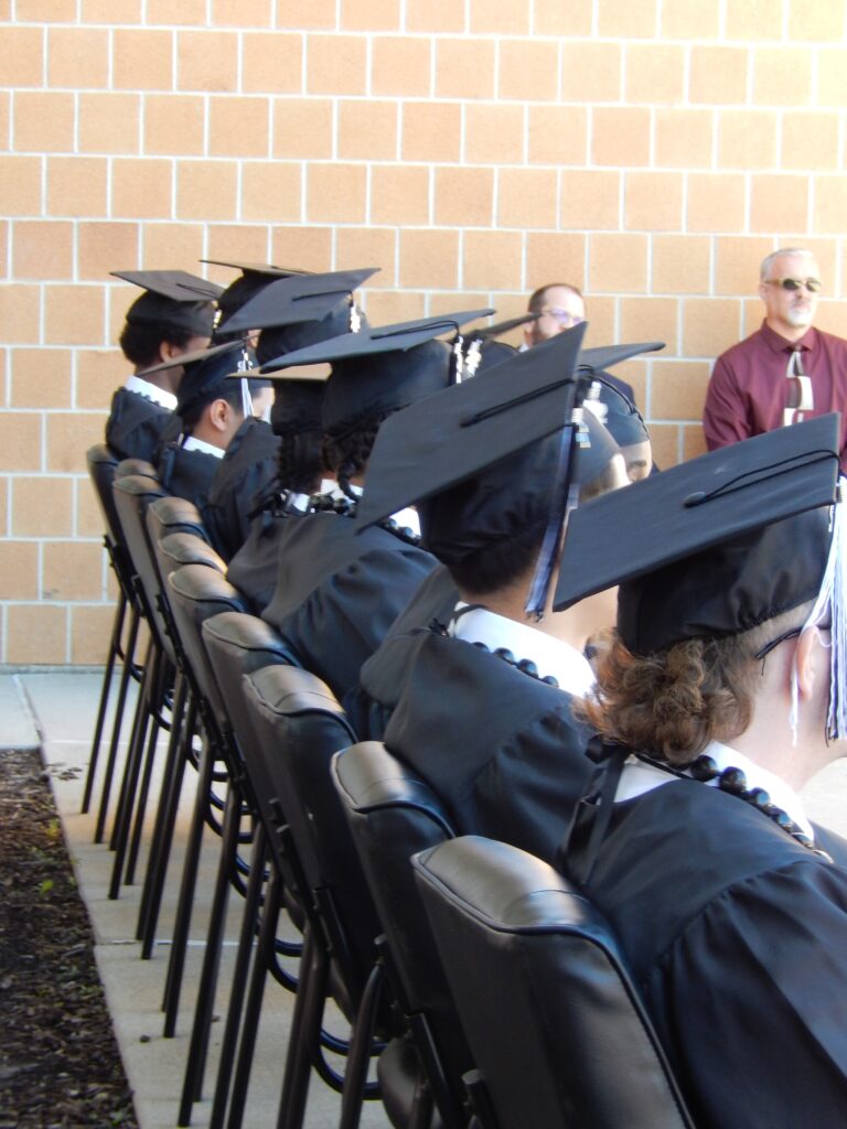 Students in cap and gowns sitting in chairs