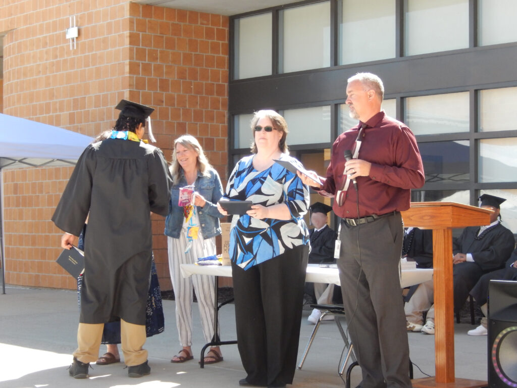 Angie and Jason giving out diploma's to graduates