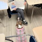 Dog sitting being read to by a student